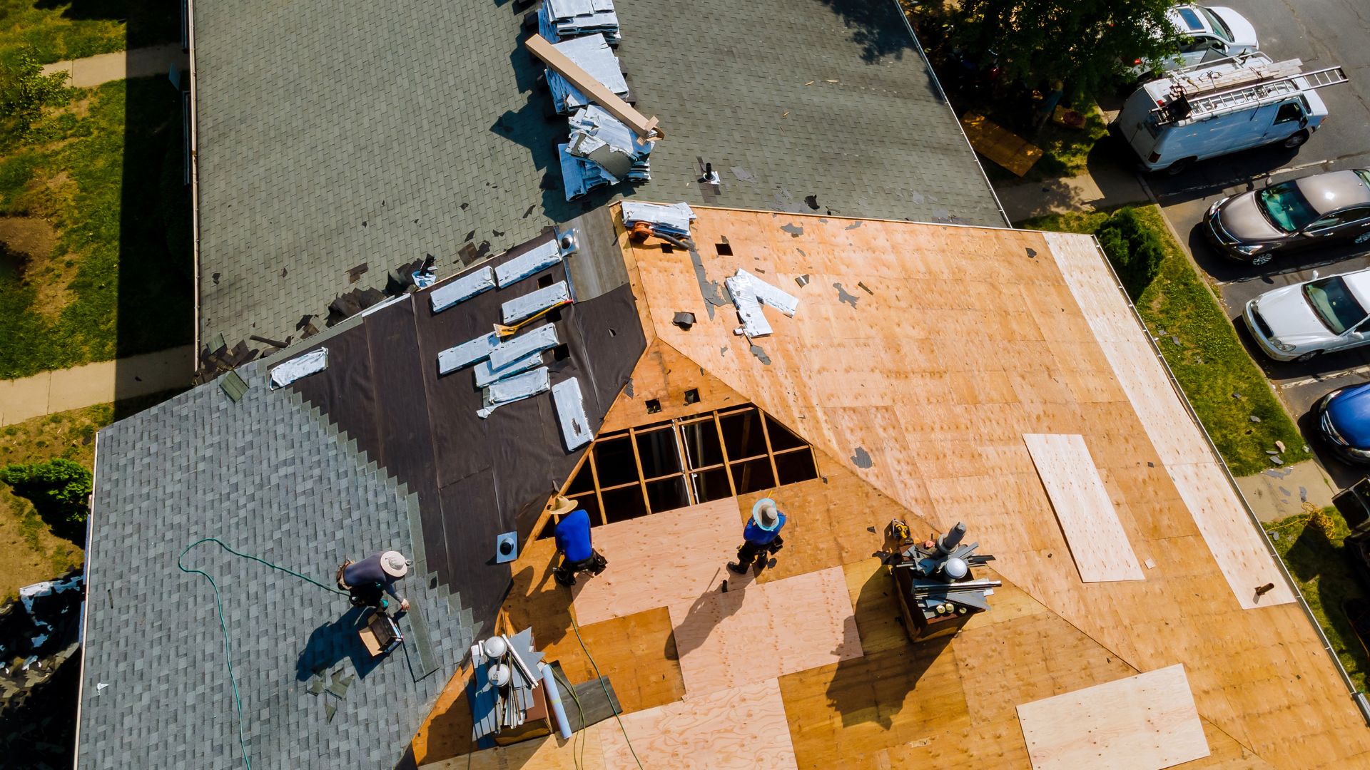 Aerial view of roofers working on a house roof with various materials